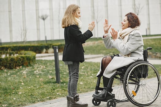servicios Happy child and woman in wheelchair sharing a joyful moment outdoors.