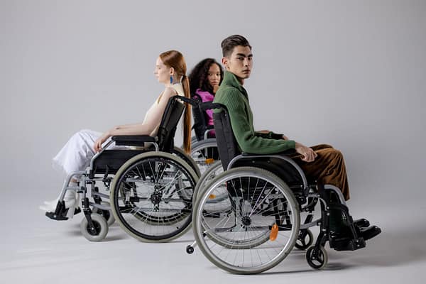 servicios Three diverse individuals in wheelchairs posing indoors, symbolizing inclusivity.